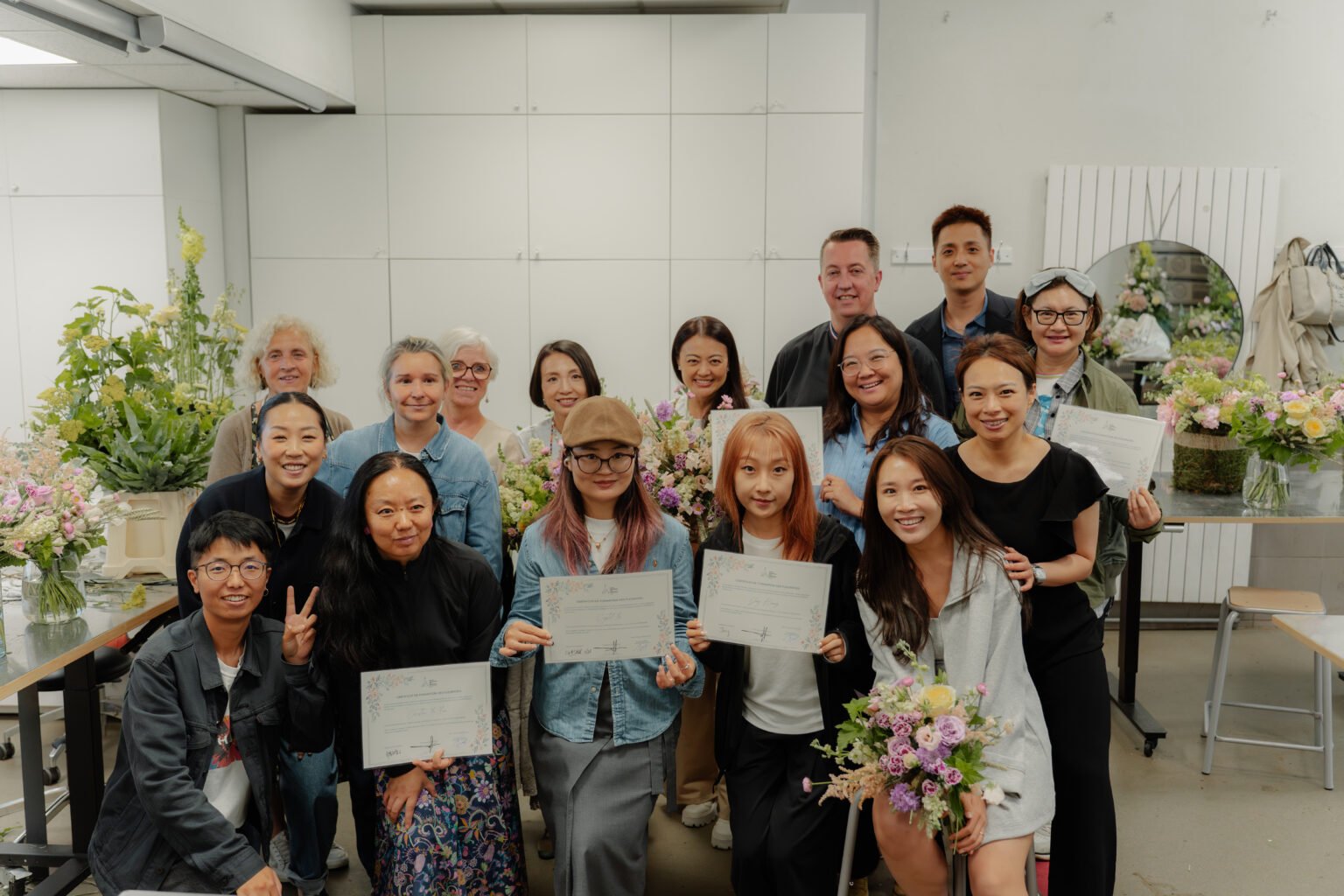 Floristry students holding certificates and arrangements